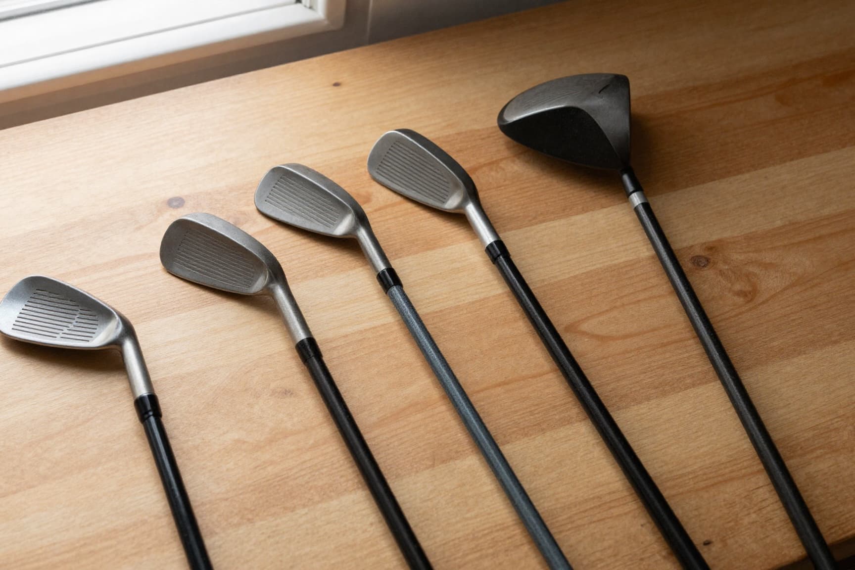 Golf irons and a driver laid out for a repair assessment